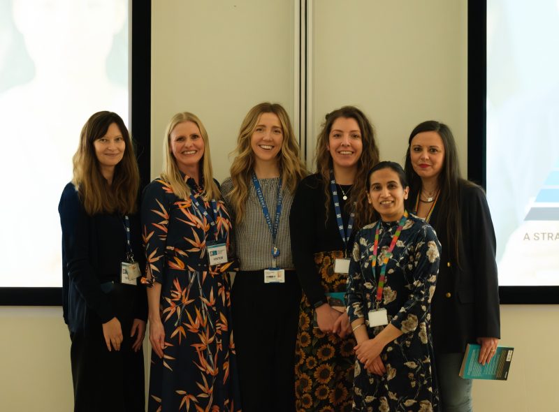 6 women standing together and smiling in a seminar room