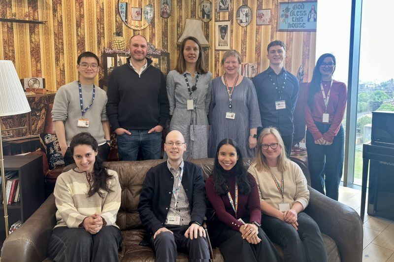 Members of the Steroids and Metabolism group stand together in front of a wallpapered background