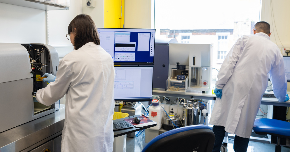 Photo of two scientists in white lab coats in a bright lab